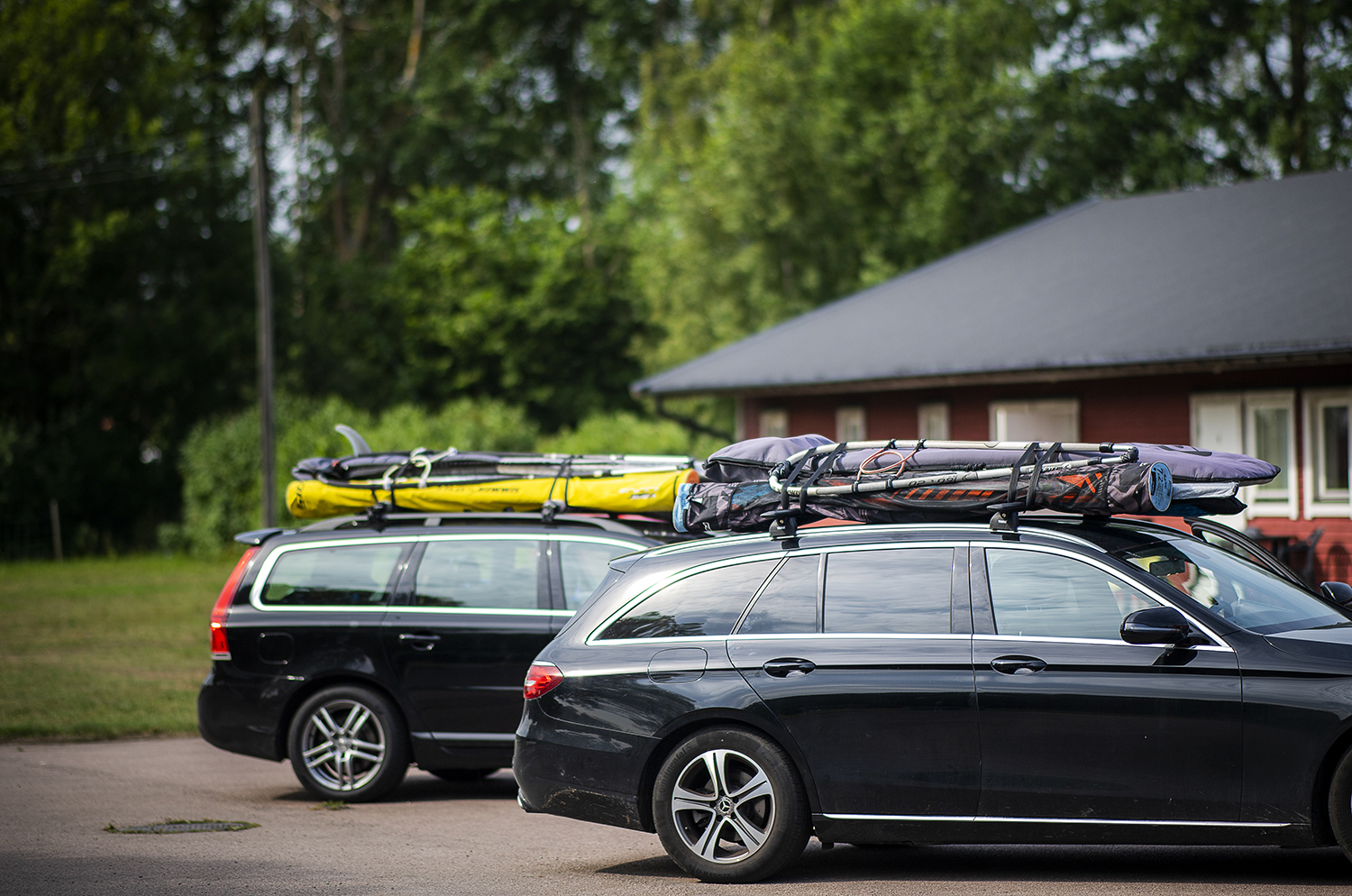 Två bilar parkerade utanför Haga Park Camping och Stugor, lastade med surfbrädor och kajaker på takräcken.