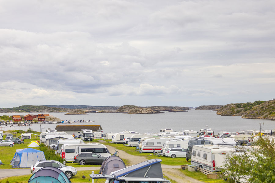 Vy över campingplatsen med havet och klippor i bakgrunden.