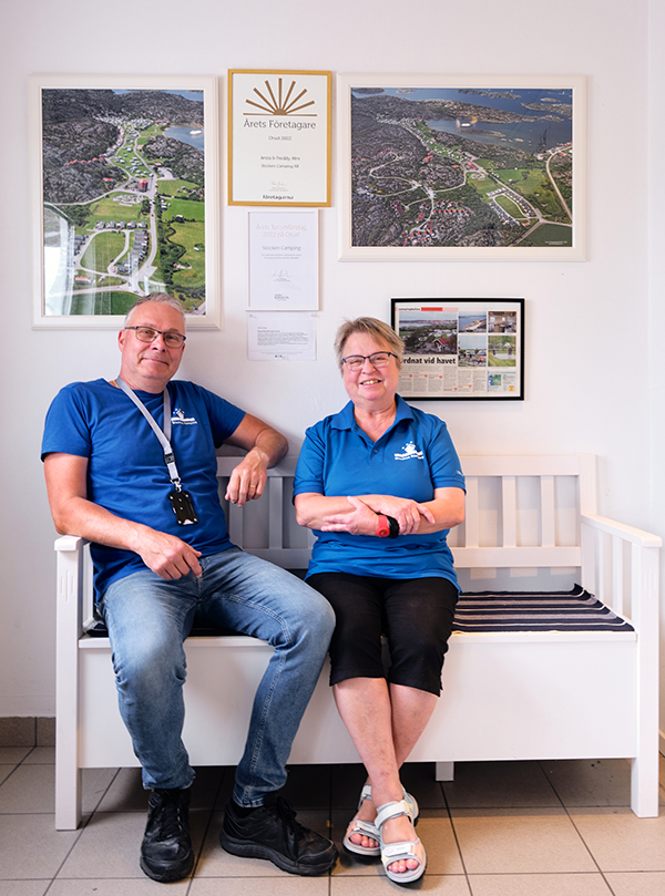 Freddy och Anita på Stocken Camping, med priset inramat ovanför bänken.